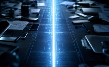 A wide, cinematic shot of a high-tech workspace cluttered with smartphones, tablets, and technical blueprints, overlaid with glowing blue digital circuitry patterns and a bright vertical beam of light.
